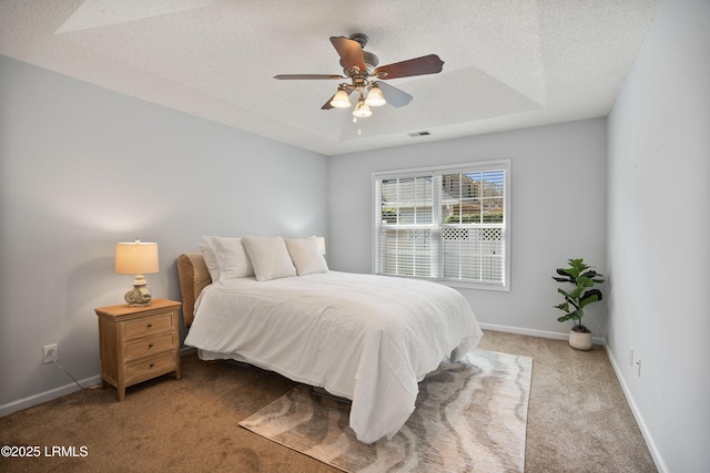 carpeted bedroom featuring ceiling fan, a tray ceiling, and a textured ceiling