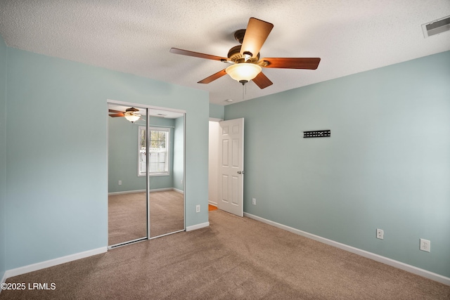 unfurnished bedroom featuring ceiling fan, carpet floors, a closet, and a textured ceiling