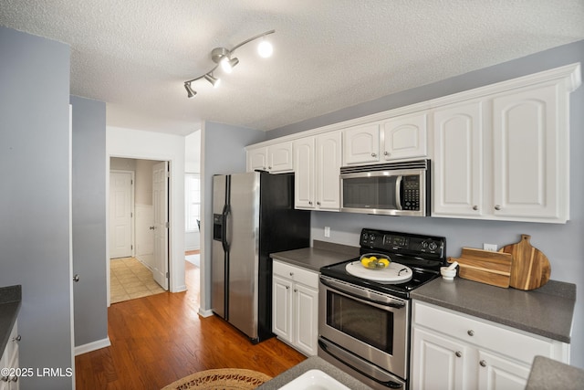 kitchen featuring white cabinetry, dark hardwood / wood-style floors, a textured ceiling, and appliances with stainless steel finishes