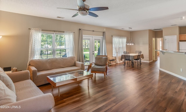 living room with dark wood-type flooring, ceiling fan, and a textured ceiling