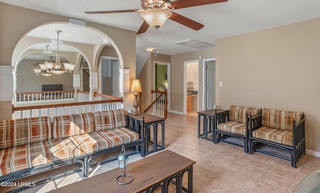 living room with ceiling fan with notable chandelier, a textured ceiling, and light tile patterned floors