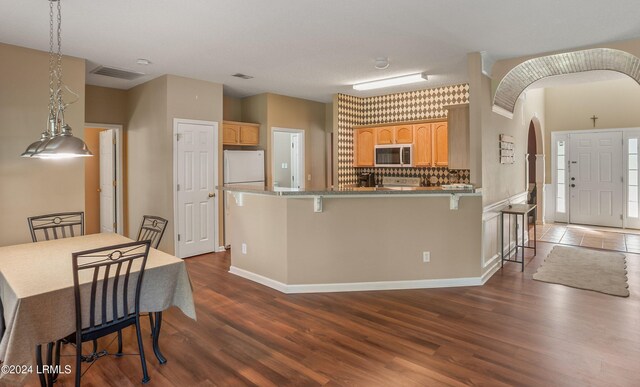 kitchen with white refrigerator, a kitchen breakfast bar, dark hardwood / wood-style flooring, and light brown cabinetry