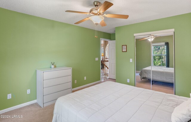 carpeted bedroom with ceiling fan, a closet, and a textured ceiling