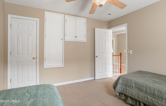 carpeted bedroom featuring ceiling fan and a textured ceiling