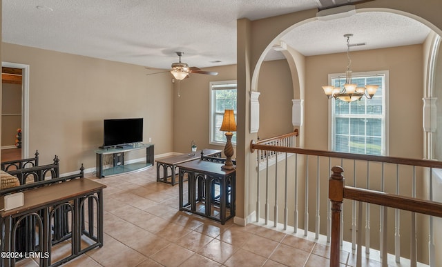 interior space with light tile patterned floors, ceiling fan with notable chandelier, and a textured ceiling