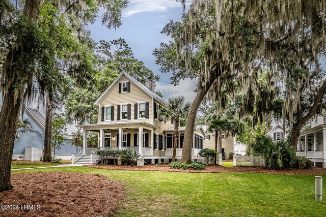 view of front of house featuring a sunroom, a front yard, and covered porch