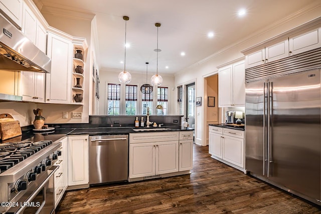 kitchen with high end appliances, decorative light fixtures, extractor fan, and white cabinets