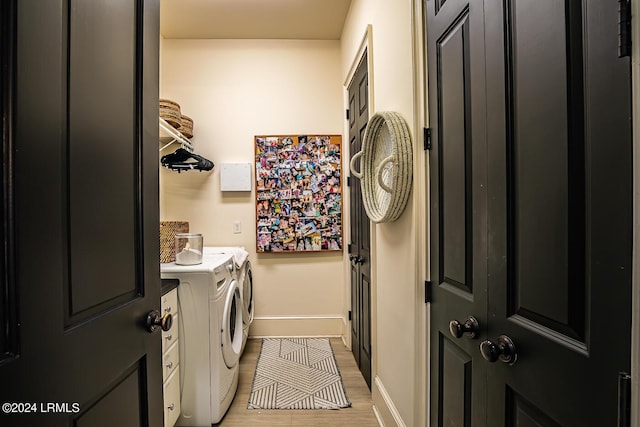 clothes washing area with washer and clothes dryer and light hardwood / wood-style flooring