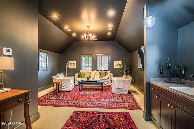 living room with an inviting chandelier, vaulted ceiling, light hardwood / wood-style floors, and sink