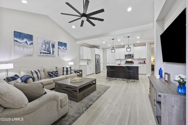 living room with ceiling fan, lofted ceiling, and light hardwood / wood-style floors