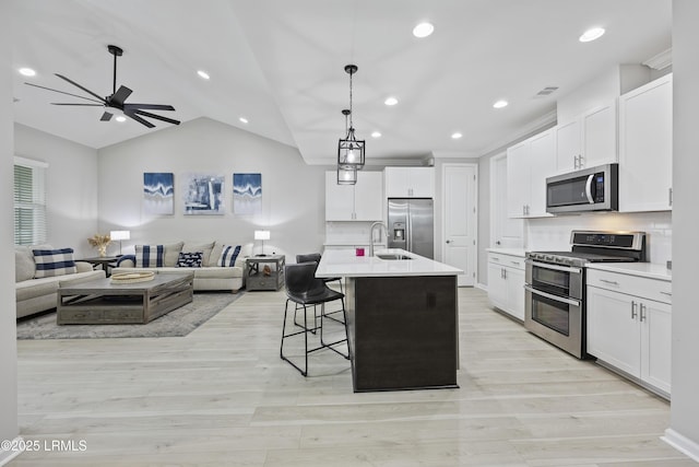 kitchen with backsplash, appliances with stainless steel finishes, an island with sink, and white cabinets