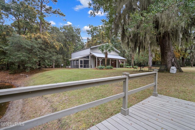 deck with a sunroom and a lawn