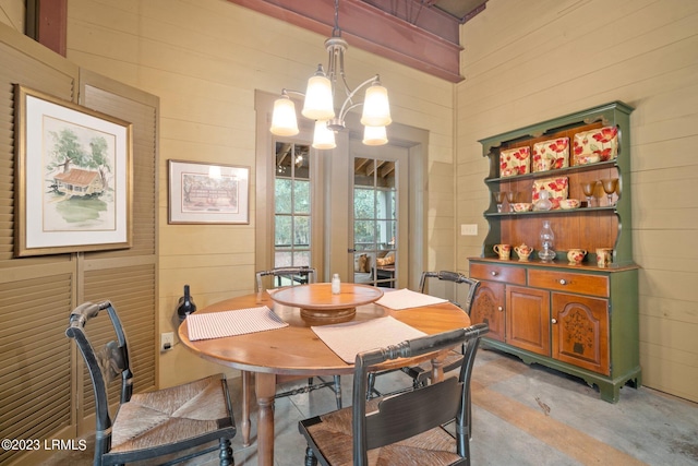 dining area with a chandelier and wood walls