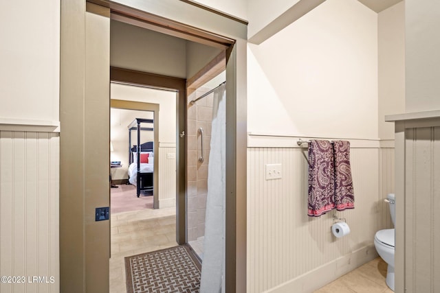 bathroom featuring tile patterned flooring, tiled shower, and toilet