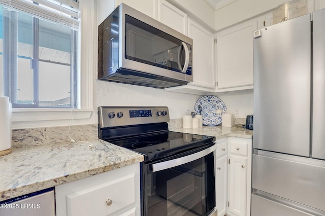 kitchen with white cabinetry, stainless steel appliances, crown molding, and light stone countertops