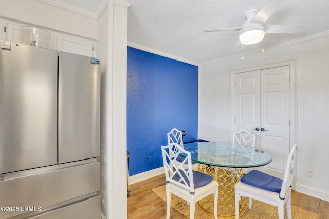 dining room with crown molding, light hardwood / wood-style floors, ceiling fan, and a textured ceiling