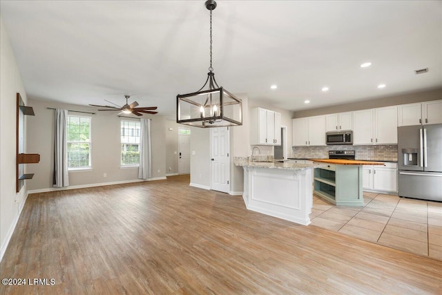 kitchen featuring white cabinetry, stainless steel appliances, butcher block countertops, and hanging light fixtures