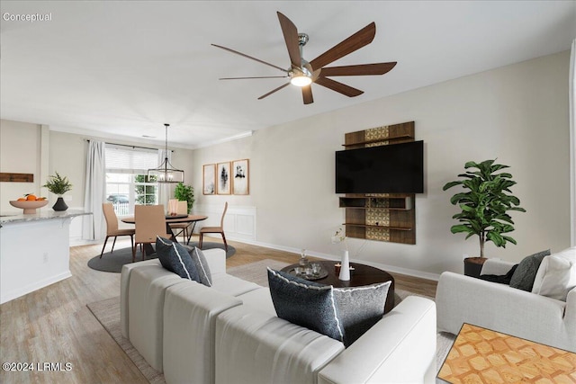 living room featuring ceiling fan with notable chandelier and light hardwood / wood-style flooring