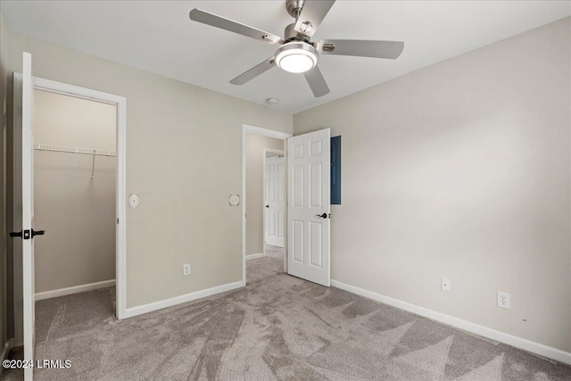 unfurnished bedroom featuring a walk in closet, light colored carpet, ceiling fan, and a closet