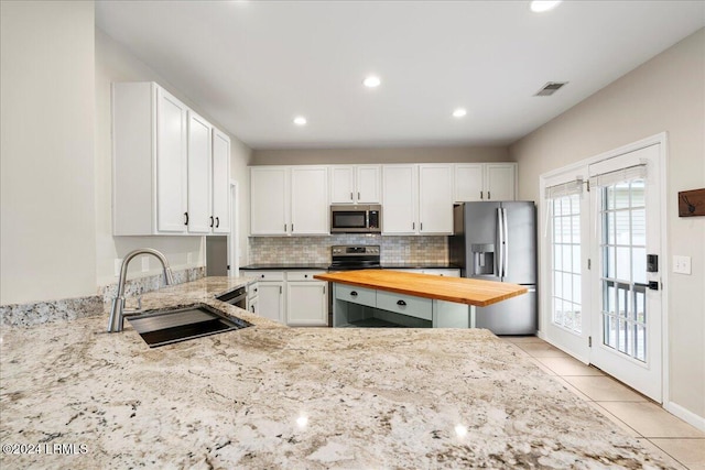 kitchen featuring stainless steel appliances, butcher block counters, sink, and white cabinets