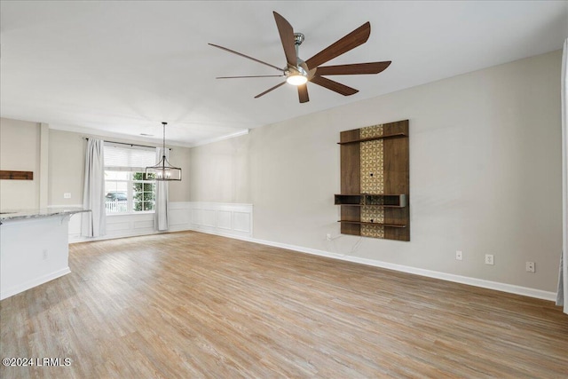 unfurnished living room featuring ceiling fan with notable chandelier and light wood-type flooring