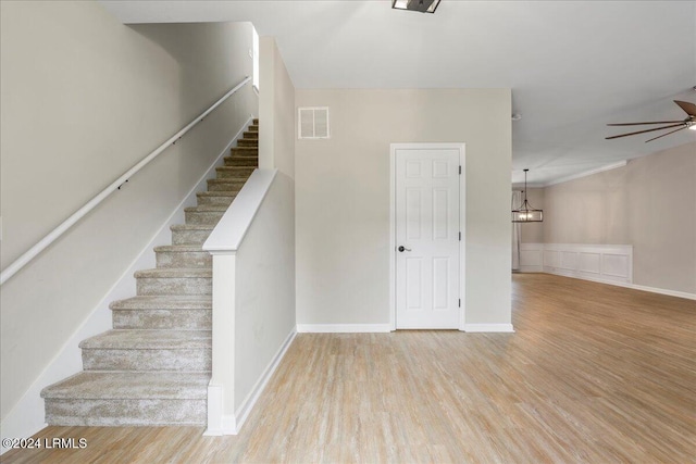 stairway with ceiling fan and wood-type flooring