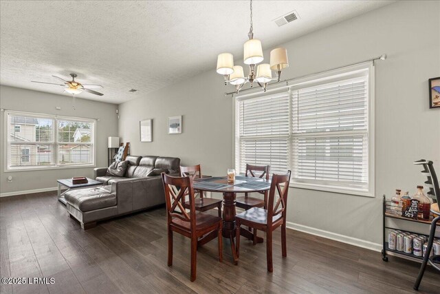 dining room with a textured ceiling, visible vents, baseboards, dark wood-type flooring, and ceiling fan with notable chandelier