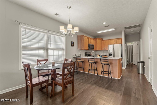 dining area with dark wood finished floors, a chandelier, and visible vents