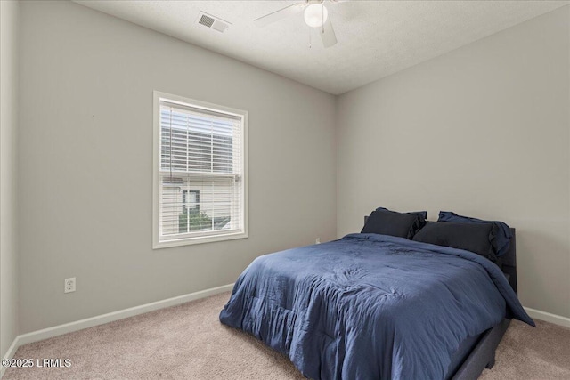 carpeted bedroom featuring baseboards, ceiling fan, and visible vents