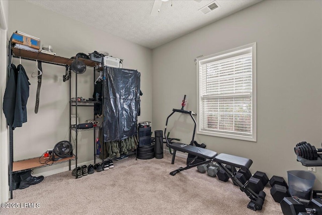 workout room featuring carpet flooring, a textured ceiling, visible vents, and a ceiling fan