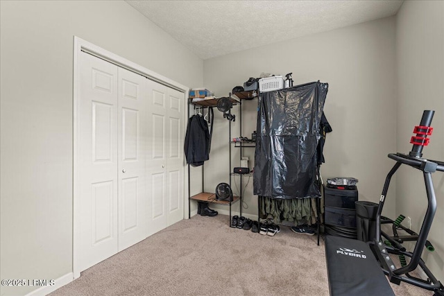 workout area with baseboards, carpet floors, and a textured ceiling