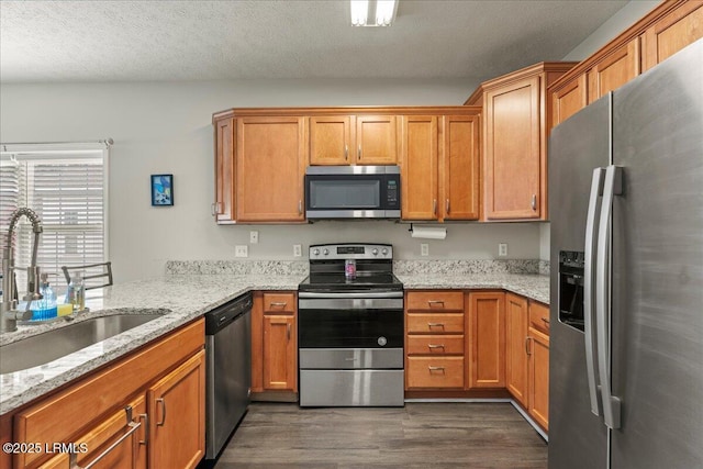kitchen featuring dark wood-style flooring, a sink, stainless steel appliances, and brown cabinetry