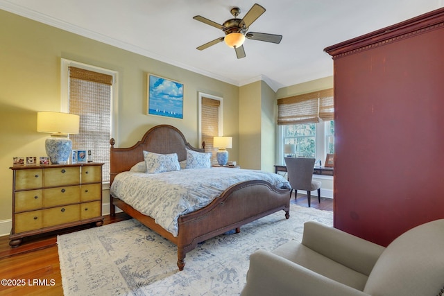 bedroom featuring ceiling fan, crown molding, baseboards, and wood finished floors