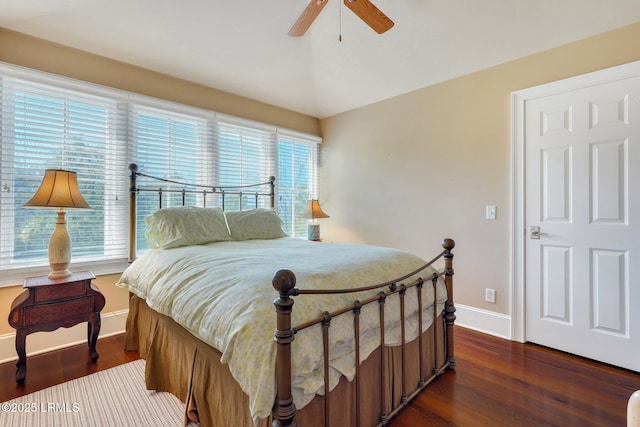 bedroom featuring ceiling fan, multiple windows, dark wood finished floors, and baseboards