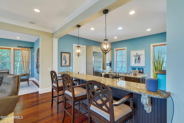 kitchen with a healthy amount of sunlight, dark wood-style floors, a kitchen breakfast bar, and built in fridge