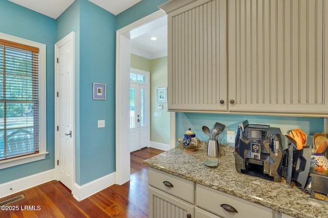 kitchen with visible vents, baseboards, cream cabinetry, light stone countertops, and dark wood finished floors