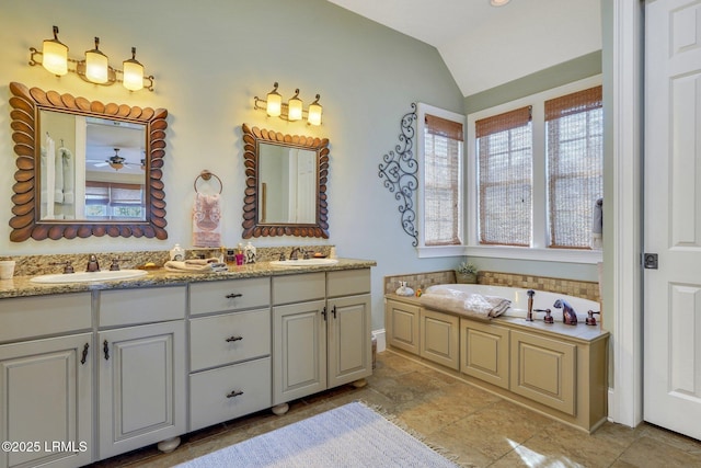 full bathroom featuring double vanity, a garden tub, vaulted ceiling, and a sink