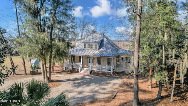 view of front facade with metal roof, a porch, a standing seam roof, and driveway