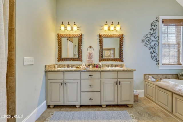 bathroom with double vanity, a sink, a bathing tub, and baseboards