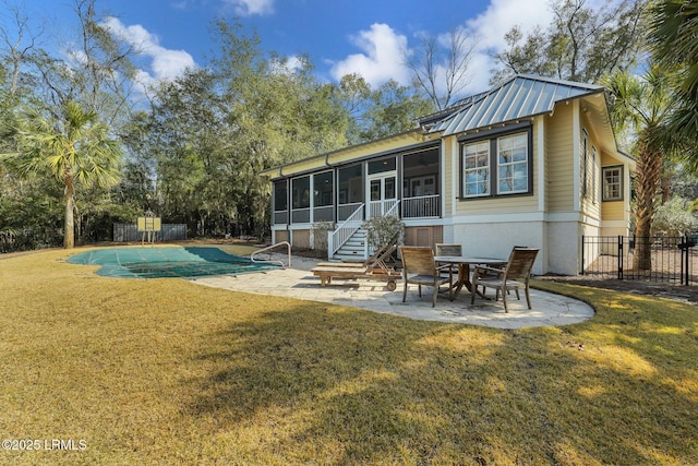 back of property featuring a patio, a sunroom, metal roof, fence, and a yard