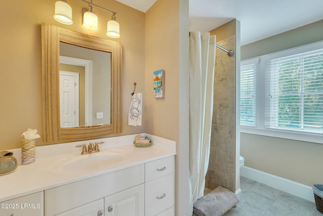 bathroom with toilet, a tile shower, vanity, and baseboards