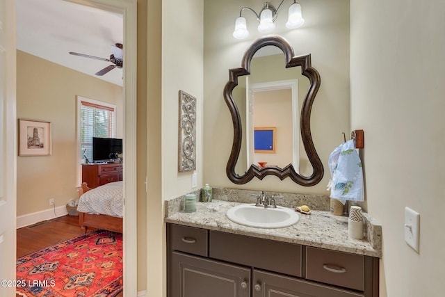 bathroom with a ceiling fan, vanity, baseboards, and wood finished floors