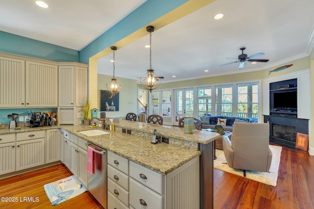 kitchen with a peninsula, a sink, cream cabinetry, dishwasher, and light wood finished floors