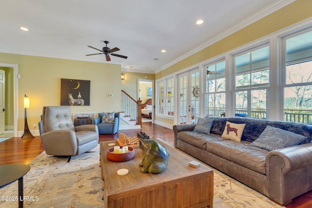 living area featuring a healthy amount of sunlight, light wood-type flooring, stairway, and crown molding