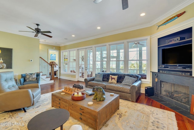 living room featuring stairs, ornamental molding, wood finished floors, and a ceiling fan