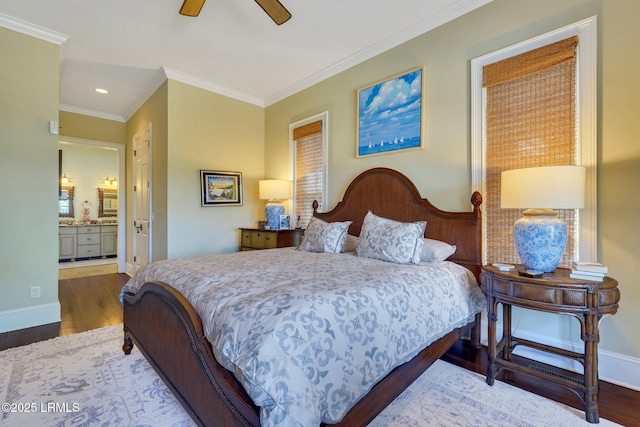 bedroom featuring ceiling fan, wood finished floors, baseboards, ornamental molding, and ensuite bath