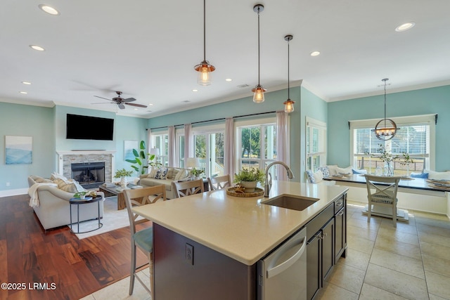 kitchen featuring ornamental molding, a stone fireplace, stainless steel dishwasher, and a sink