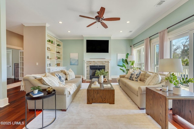 living area with recessed lighting, a fireplace, wood finished floors, visible vents, and crown molding