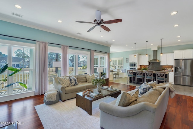 living room with recessed lighting, wood-type flooring, visible vents, and ornamental molding