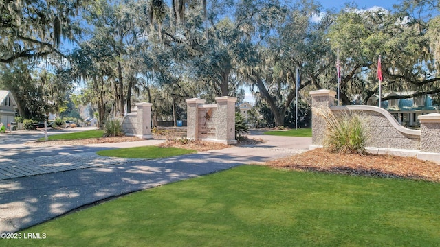 community sign with driveway and a lawn